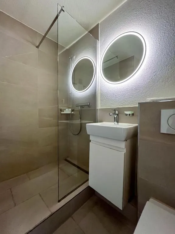 Modern bathroom with round mirrors and walk-in shower