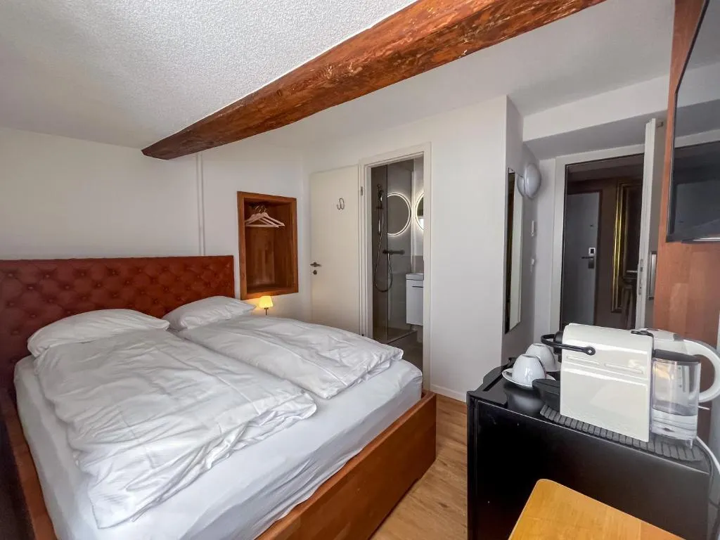 Double room with red velvet headboard and wooden beams at stattHotel Zurich